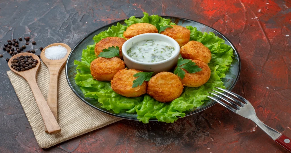 Golden brown Southern salmon patties served on a white plate with lemon wedges and fresh herbs.